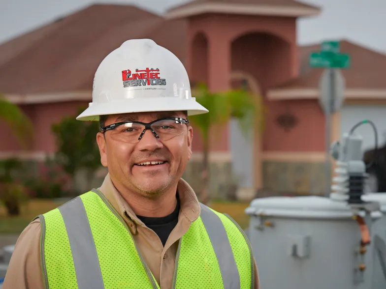 A closeup of Linetec worker in a hard hat and safety glasses smiling in Laredo, Texas.