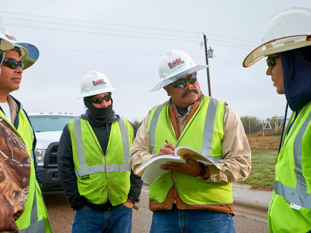 A Linetec manager records data while listening to a group of workers.
