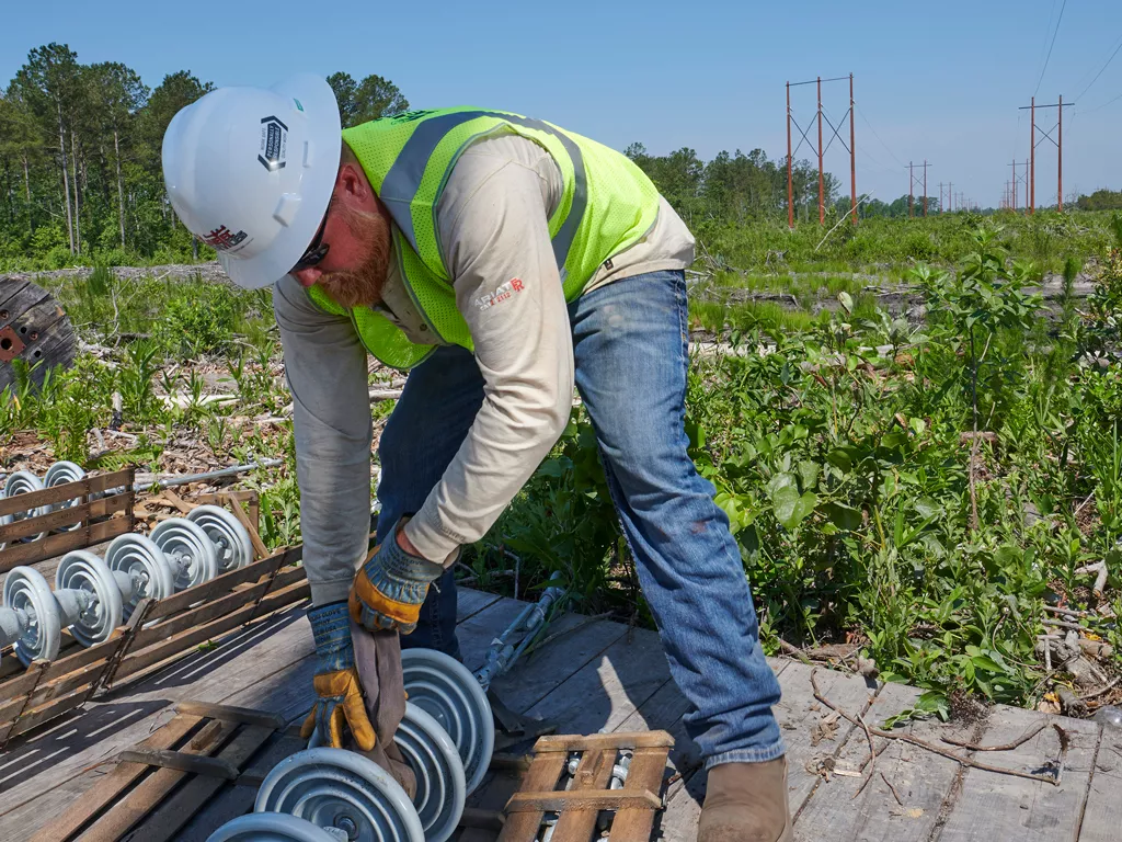 A Linetec employee works on electrical equipment in a field. 