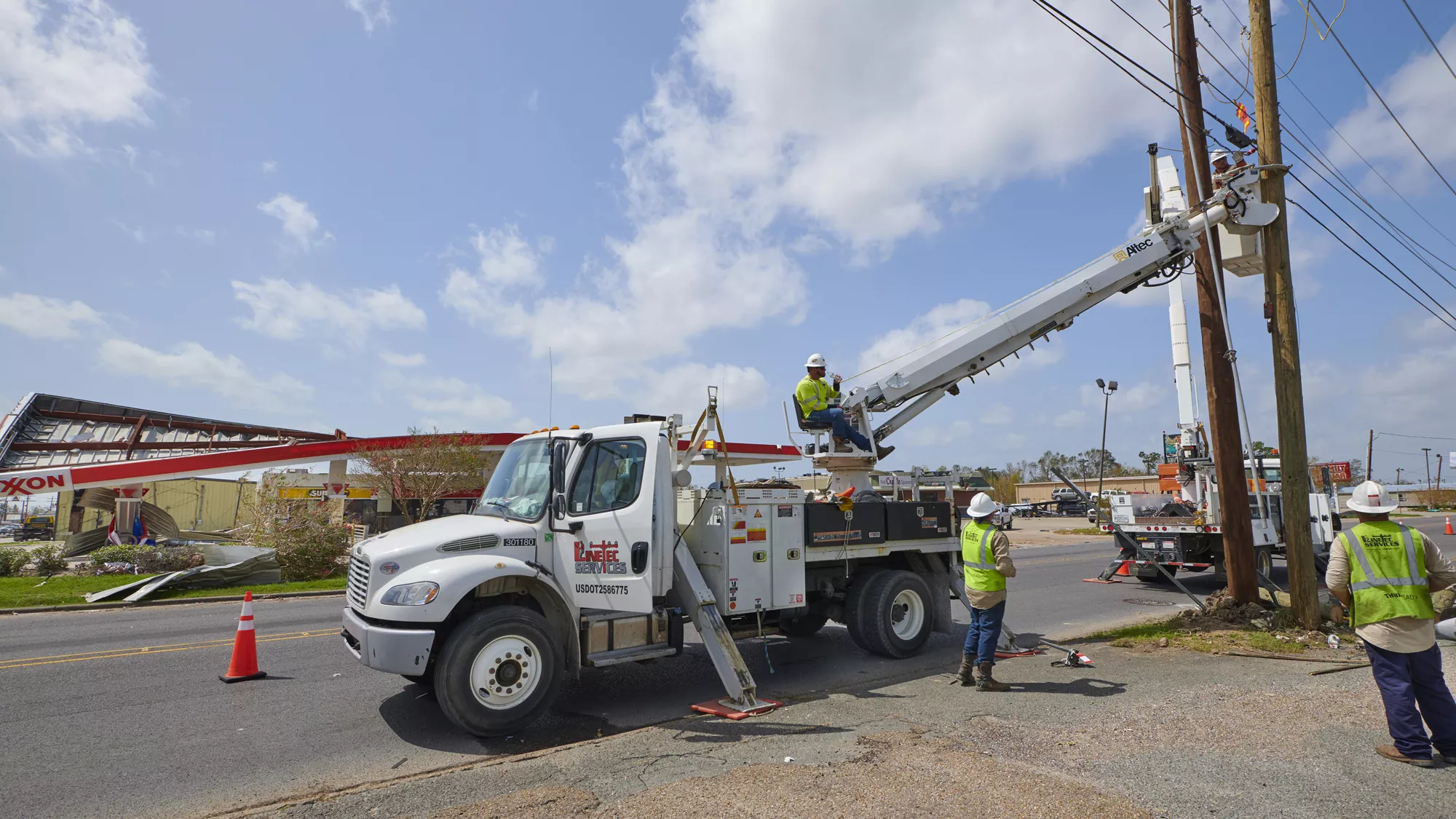 Linetec workers fix poles outdoors.