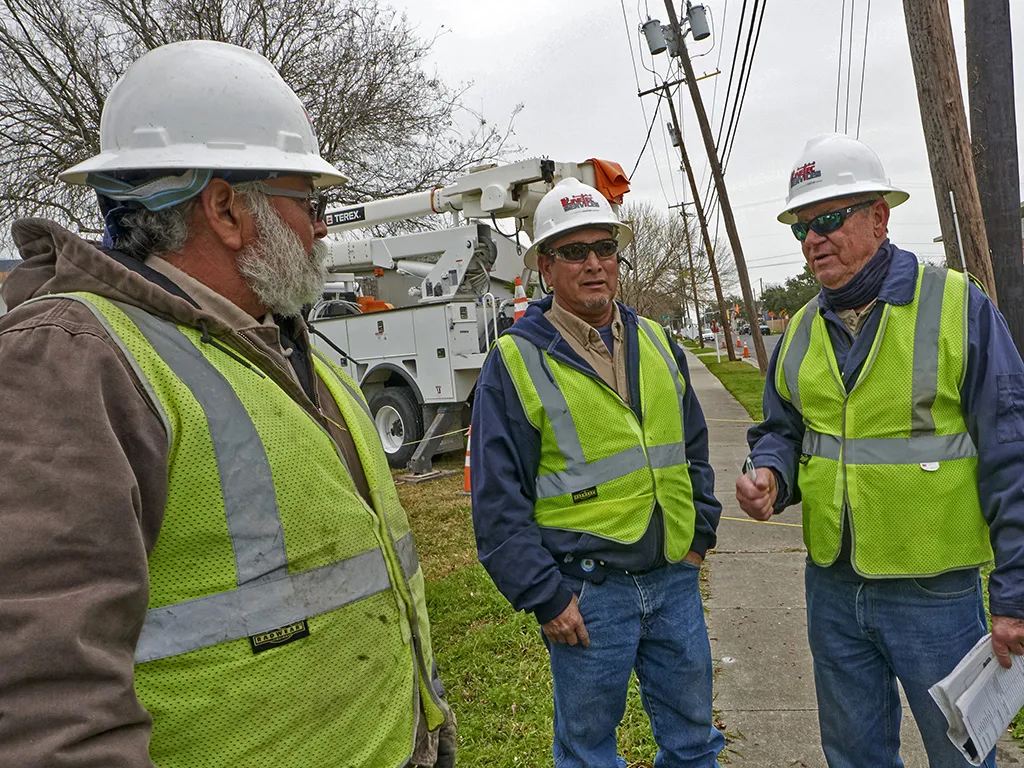 Linetec workers in hard hats and safety goggles discuss a project on location.