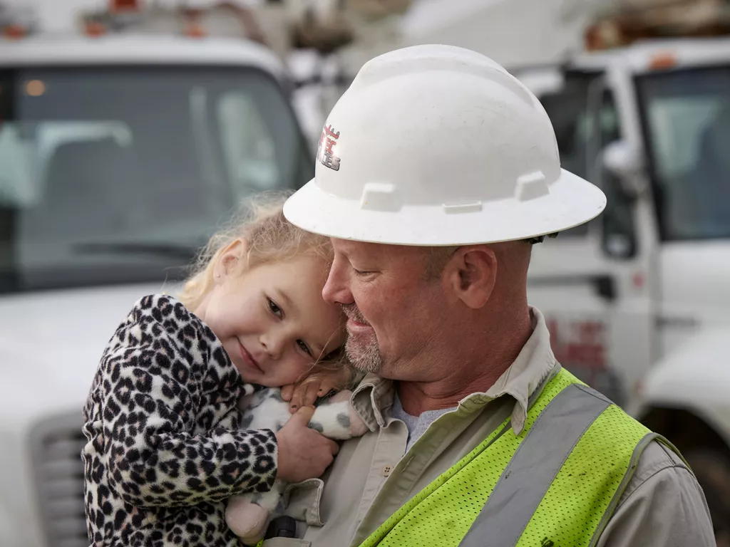 A Linetec worker holds a little girl smiling.