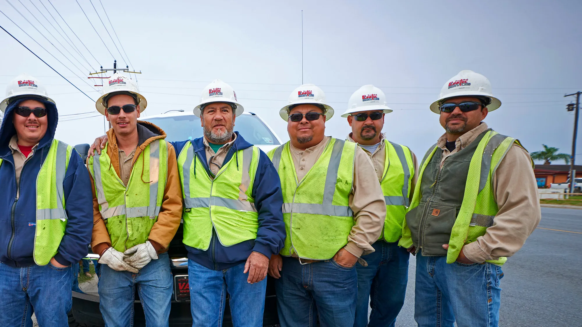 A team of Linetec workers in safety vests and hard hats smile together on a worksite in Harlingen, Texas.